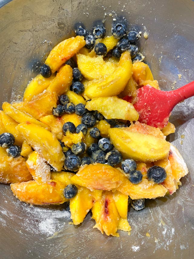 stirring peach blueberry tart filling together in bowl