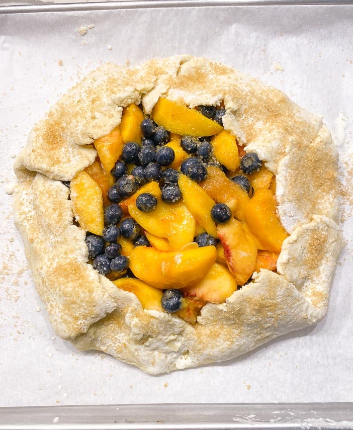 unbaked peach blueberry crostata sprinkled with raw sugar