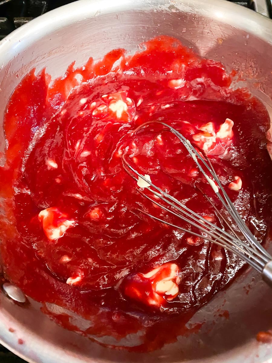 whisking butter into cranberry purée in saucepan with whisk