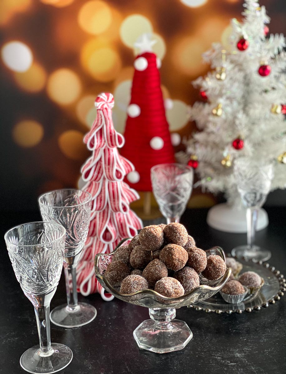 Low FODMAP Chocolate Whiskey Balls in decoratoive glass dishes against Christmas table decor, vertical image