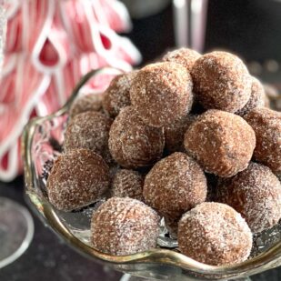 Main close shot of Low FODMAP Chocolate Whiskey Balls in decoratoive glass dishes against Christmas table decor
