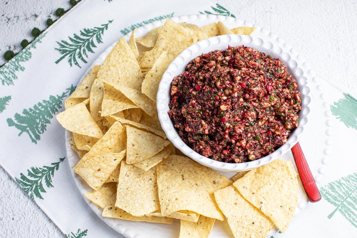 low FODMAP Cranberry Salsa in white bowl with chips on placemat