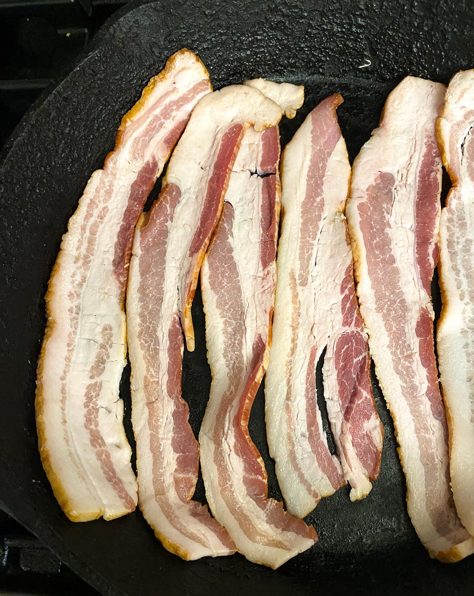 raw bacon in cast iron pan