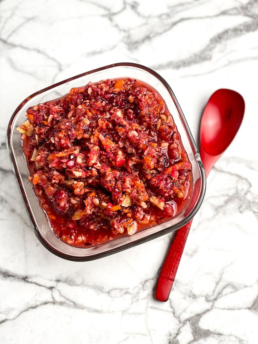vertical image of low FODMAP Raw Cranberry Relish in square glass bowl