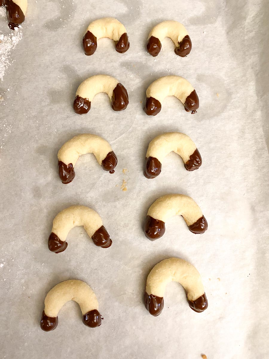 Low FODMAP Vanilla Crescents dipped in chocolate on pan