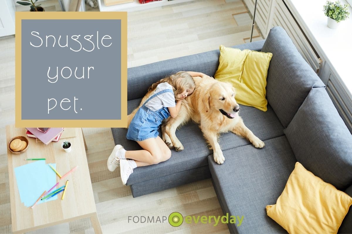 birds eye view of a young girl snuggling with her golden retriever on a grey couch.