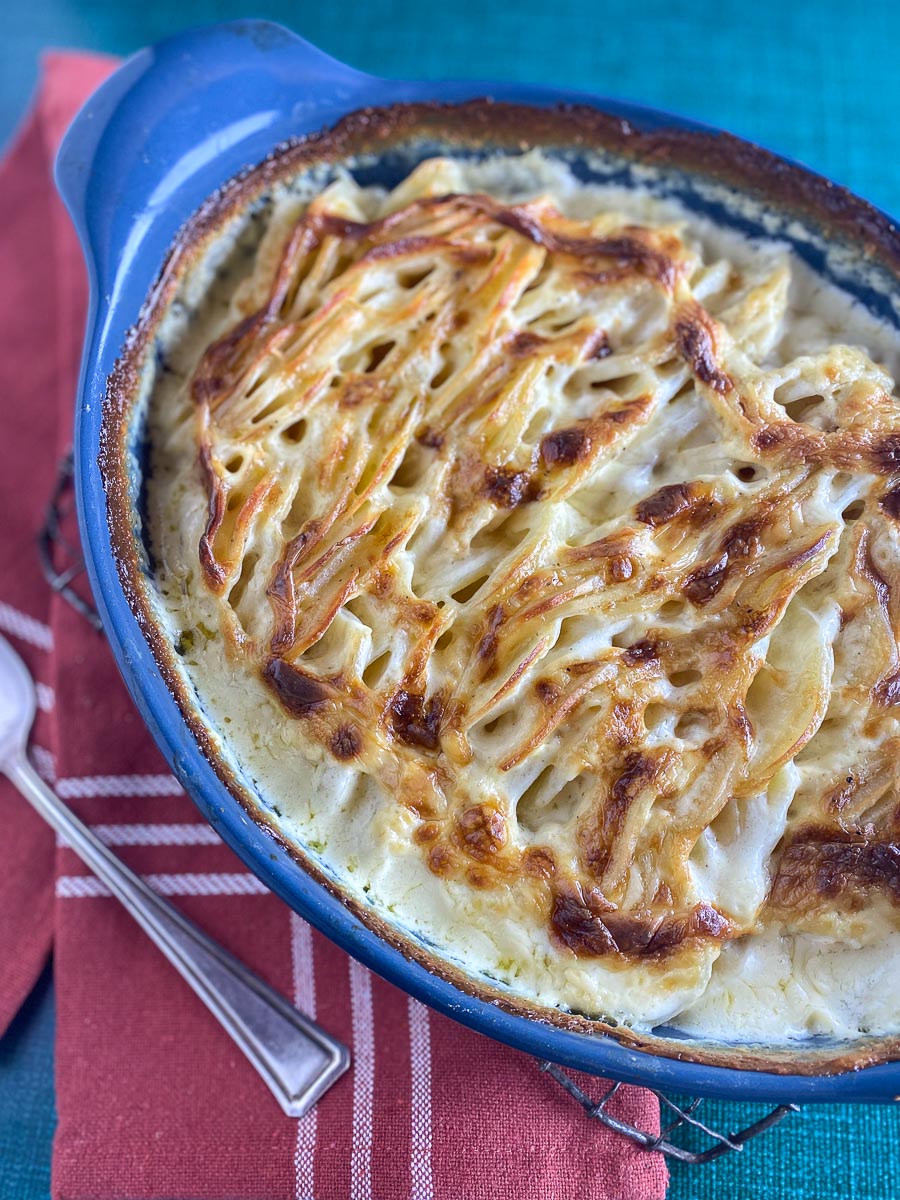 overhead image of scalloped potatoes in blue oval dish