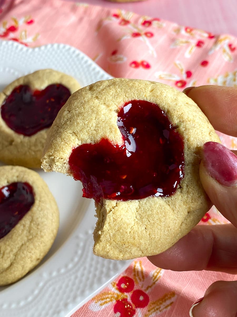 Low FODMAP Peanut BUtter & Jam Heart cookies held in hand; bite out