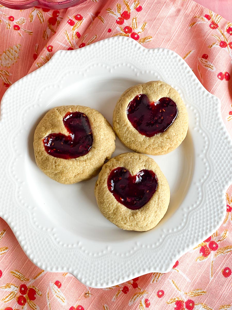 Low FODMAP Peanut BUtter & Jam Heart cookies on white plate and decorative napkin closeup