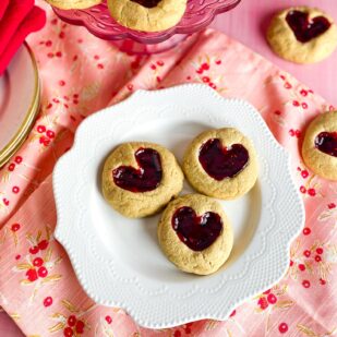 Low FODMAP Peanut Butter and Jam Hearts cookies on white plate; red napkins alongside
