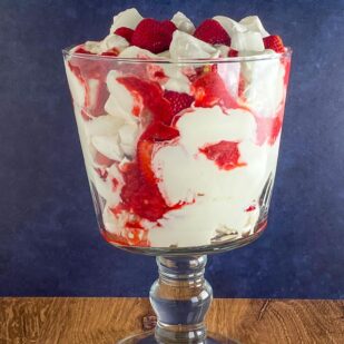 Low FODMAP Eton Mess in glass trifle bowl on wooden table, horizontal image