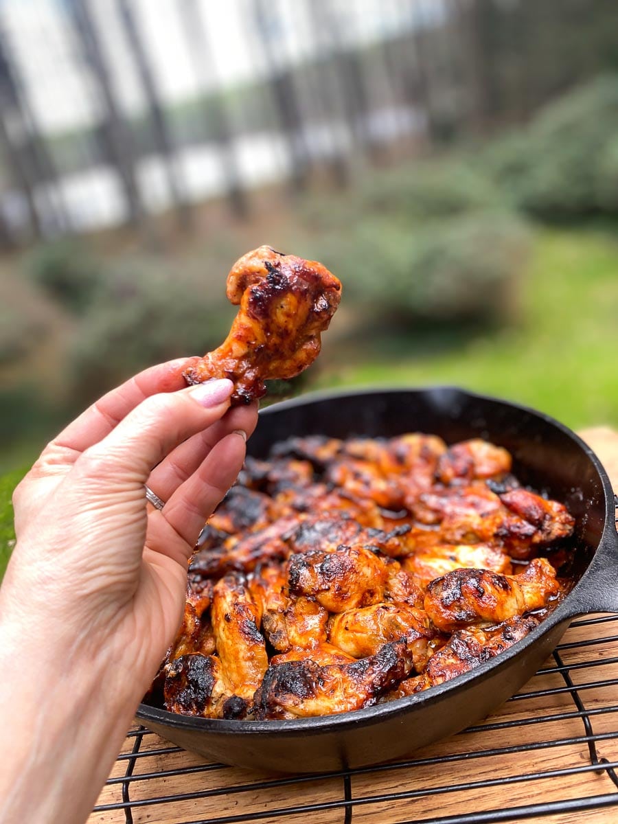 Low FODMAP Hot Honey Chicken Wings in cast iron pan and held in hand over pan