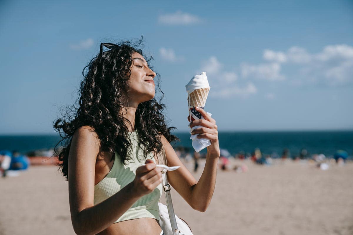 woman eating ice cream cone at beach