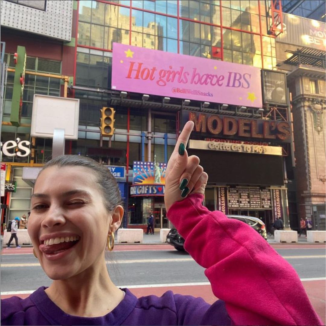 girl pointing at hot girls with ibs billboard in times square