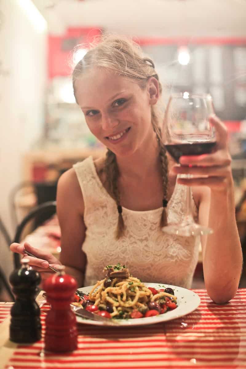 Woman eating spaghetti and drinking wine