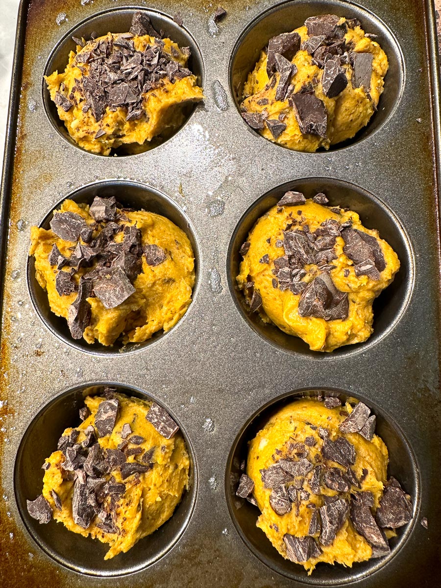 low FODMAP Pumpkin Chocolate Chunk Muffins batter scooped into muffin pans, topped with extra chocolate chunks