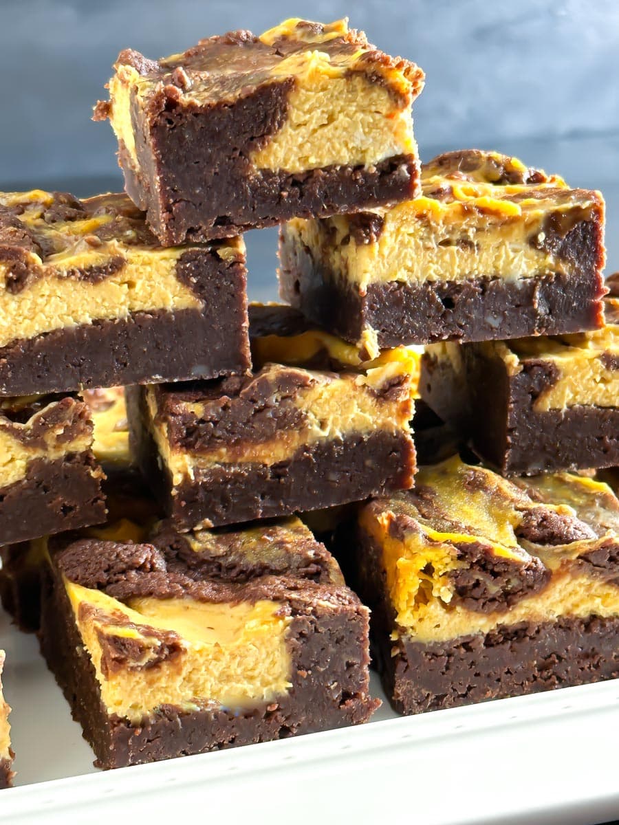 stack of low FODMAP Pumpkin Cheesecake brownies on white plate