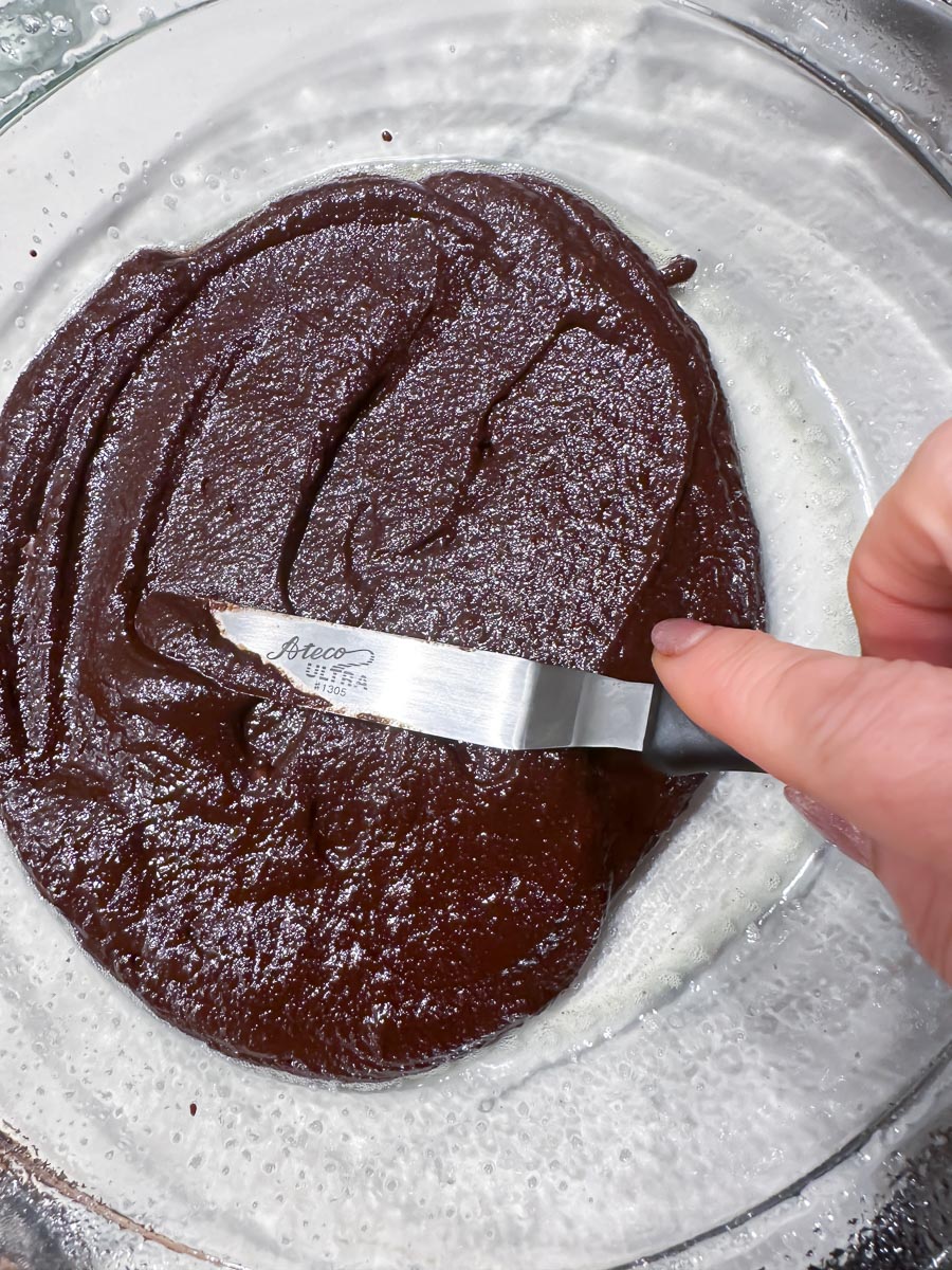 using small offset spatula to spread brownie batter in glass pie dish