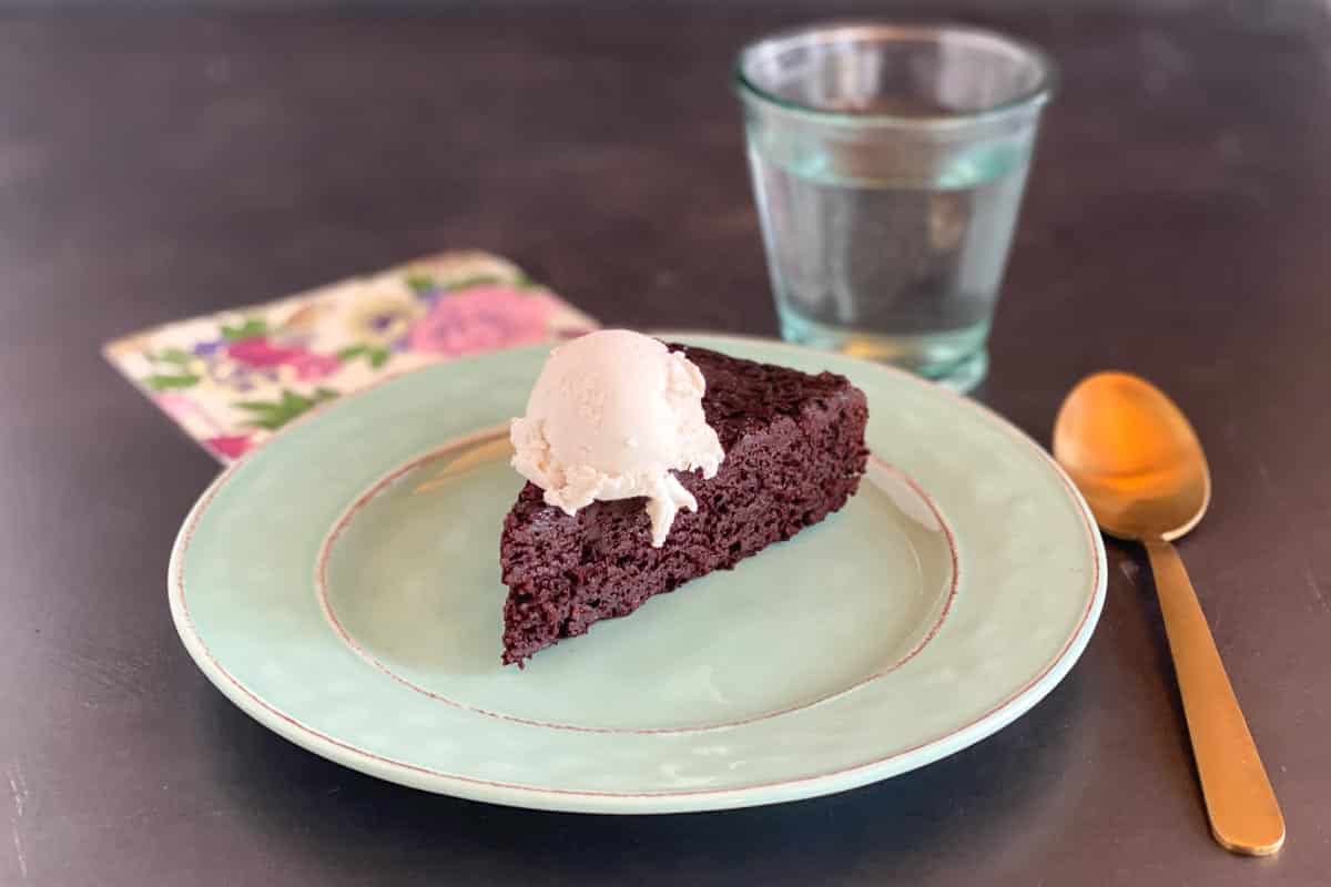wedge of very simple Low FODMAP Maple Mocha Cake on aqua plate with vanilla ice cream melting on top