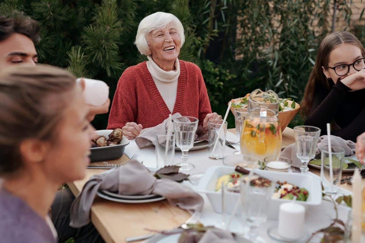 white haired woman, family and friend enjoying a meal