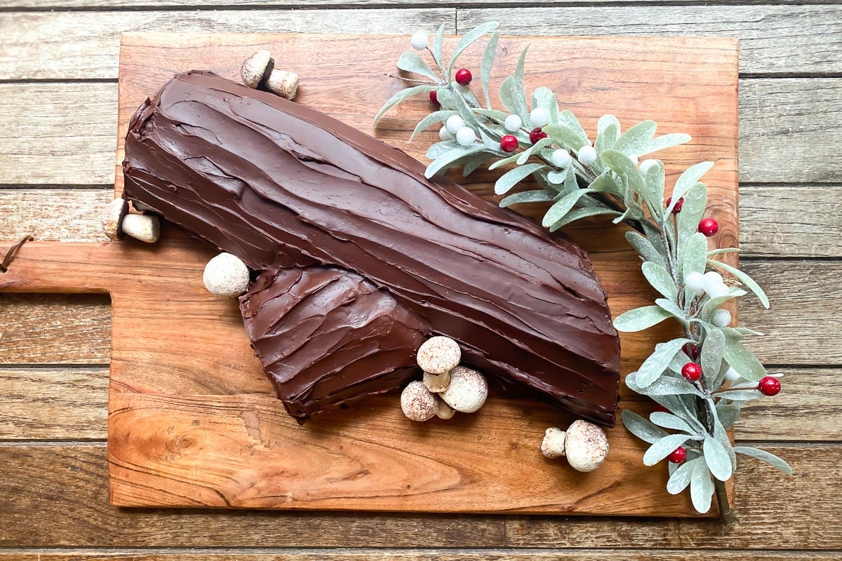 overhead image of Low FODMAP Chocolate Raspberry Buche de Noel on wooden board, with meringue mushrooms