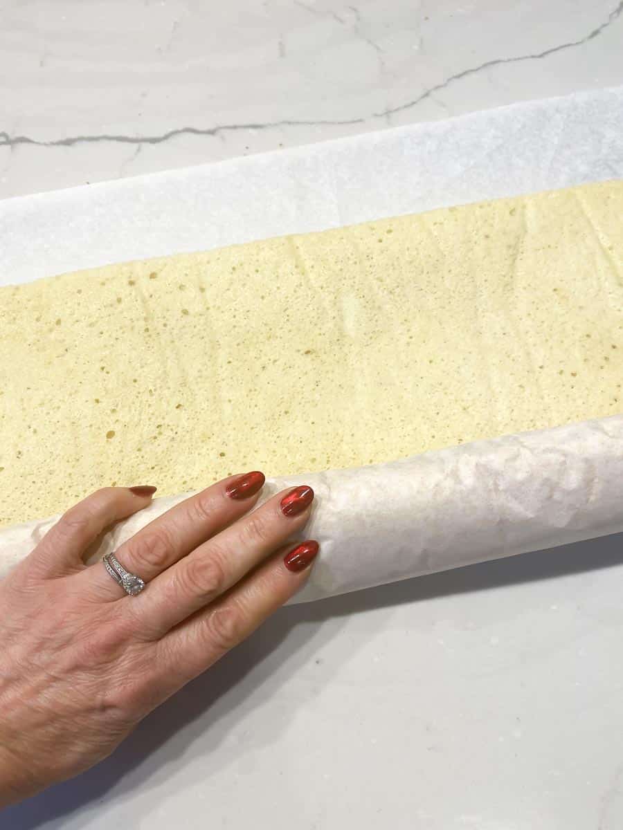 rolling up jelly roll cake in parchment