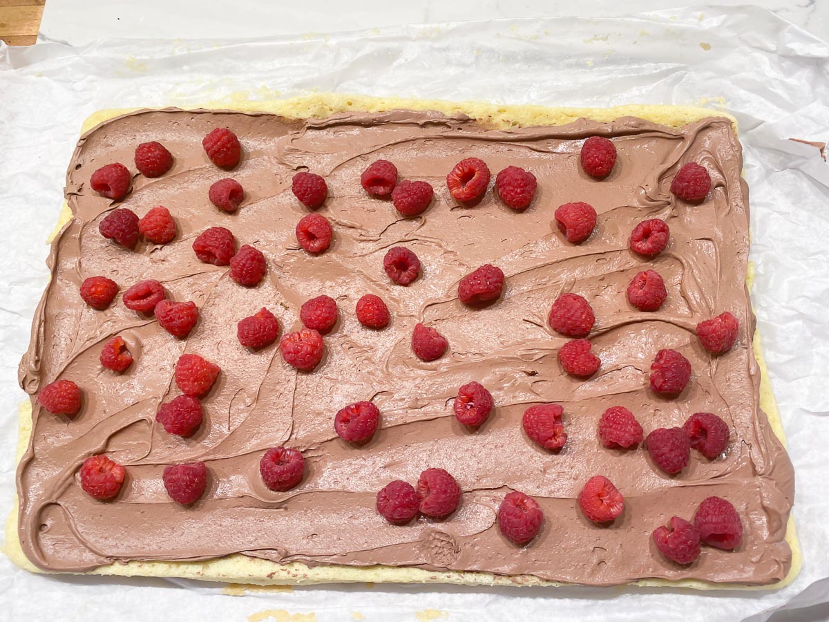 whipped ganache spread on cake with fresh raspberries