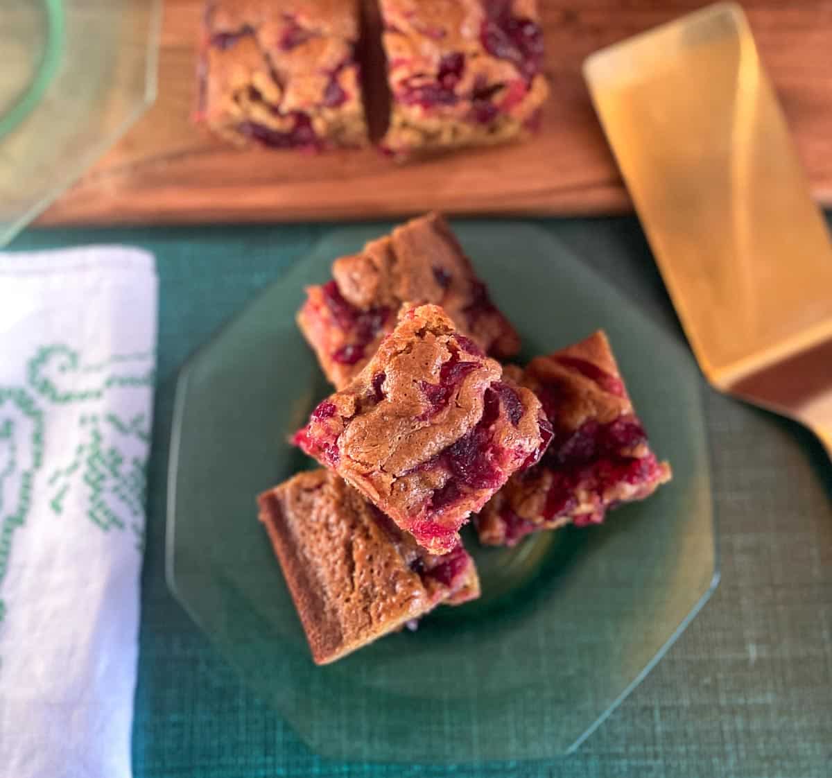 Low FODMAP Sticky Cranberry Gingerbread cut into squares, close up, on wooden board and on glass plate
