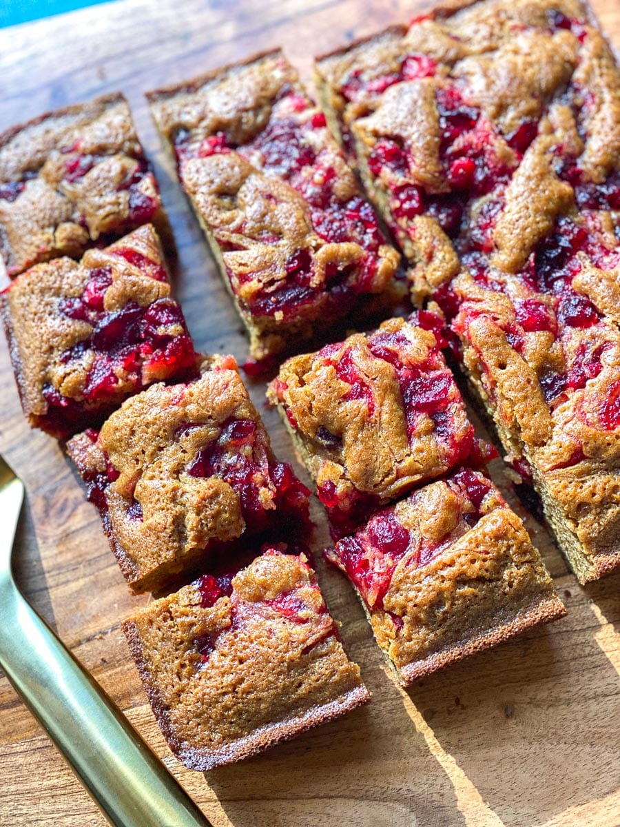 Low FODMAP Sticky Cranberry Gingerbread cut into squares, close up, on wooden board