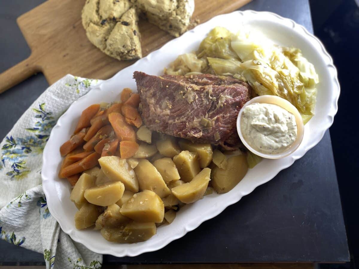 Low FODMAP Slow Cooker Corned Beef on oval white platter with cabbage, carrots and potatoes