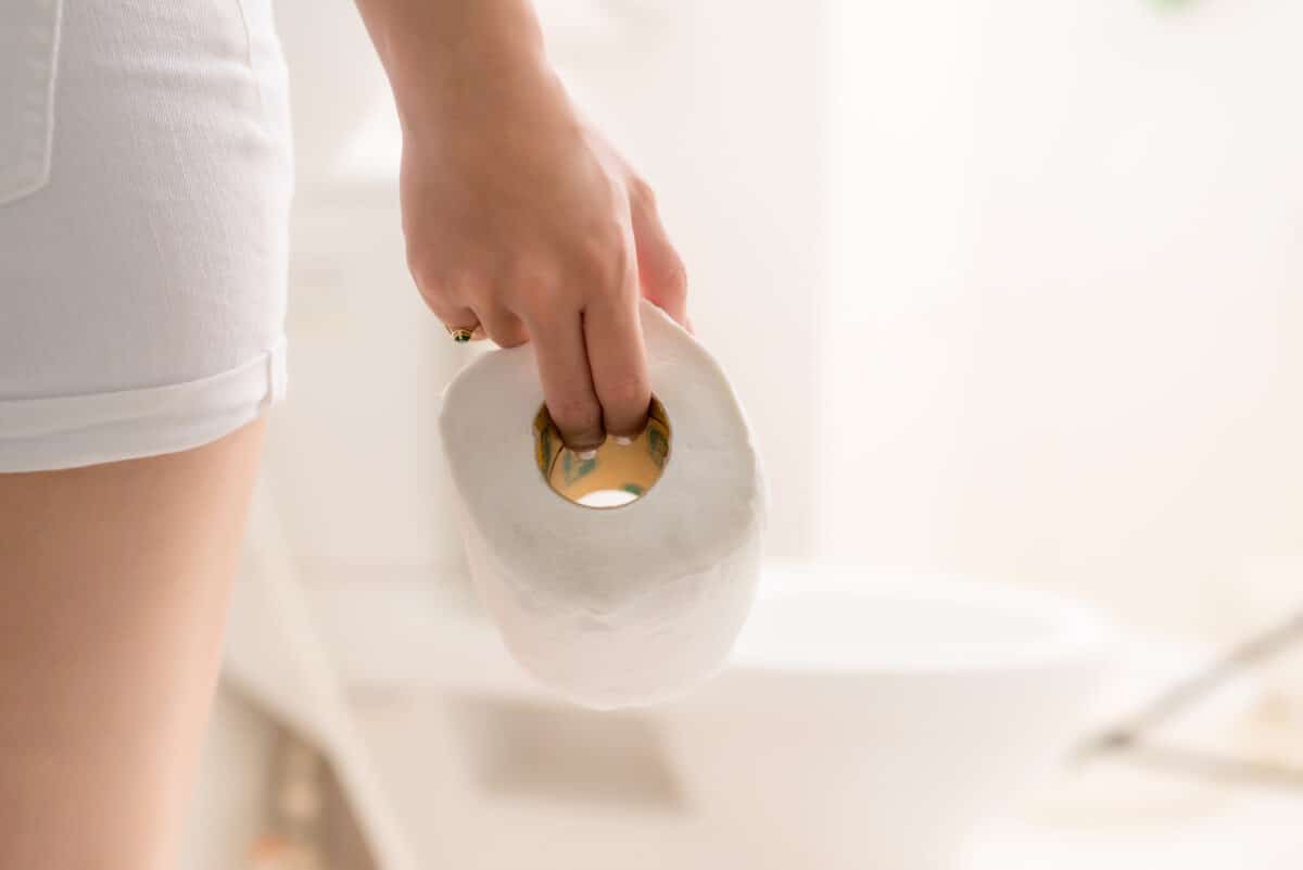 Cropped image of woman's hand take toilet paper in the bathroom