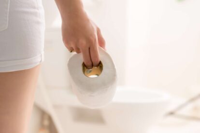 Cropped image of woman's hand take toilet paper in the bathroom