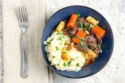 Instant pot beef stew served with mashed potatoes on a blue plate.