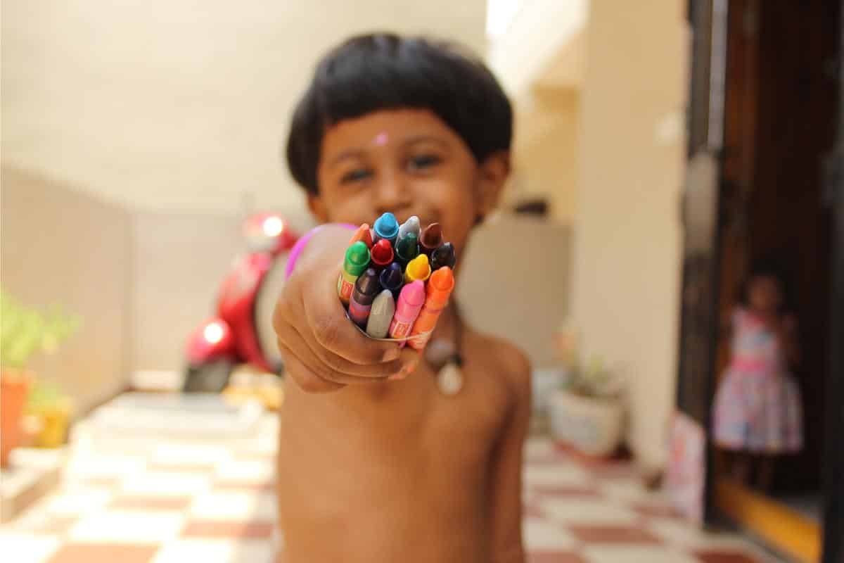 Kid holding crayons.