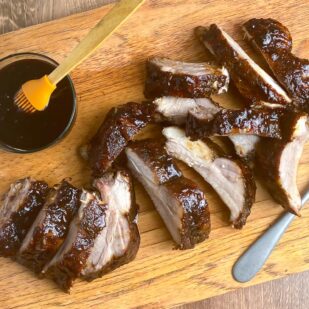 Low FODMAP 5-Spice Ribs with Plum sauce on board and with bowl of sauce.