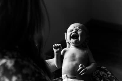baby crying held in hands.