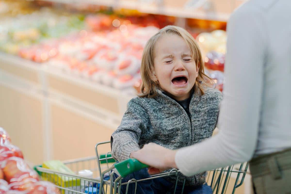 child crying in shopping cart.