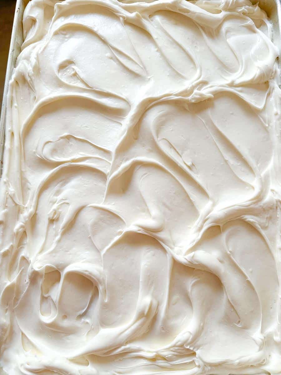 creamy frosting spread on cake in pan.