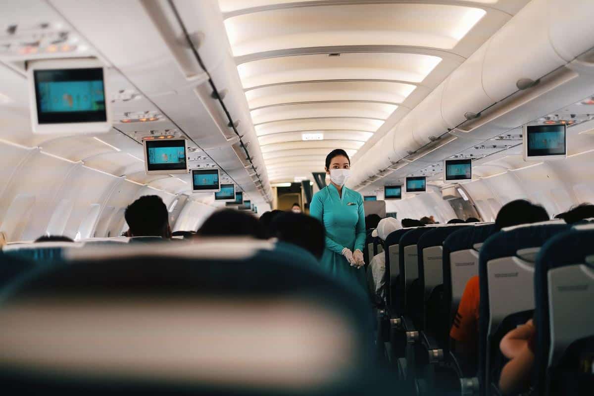 female airline steward in aisle of plane.