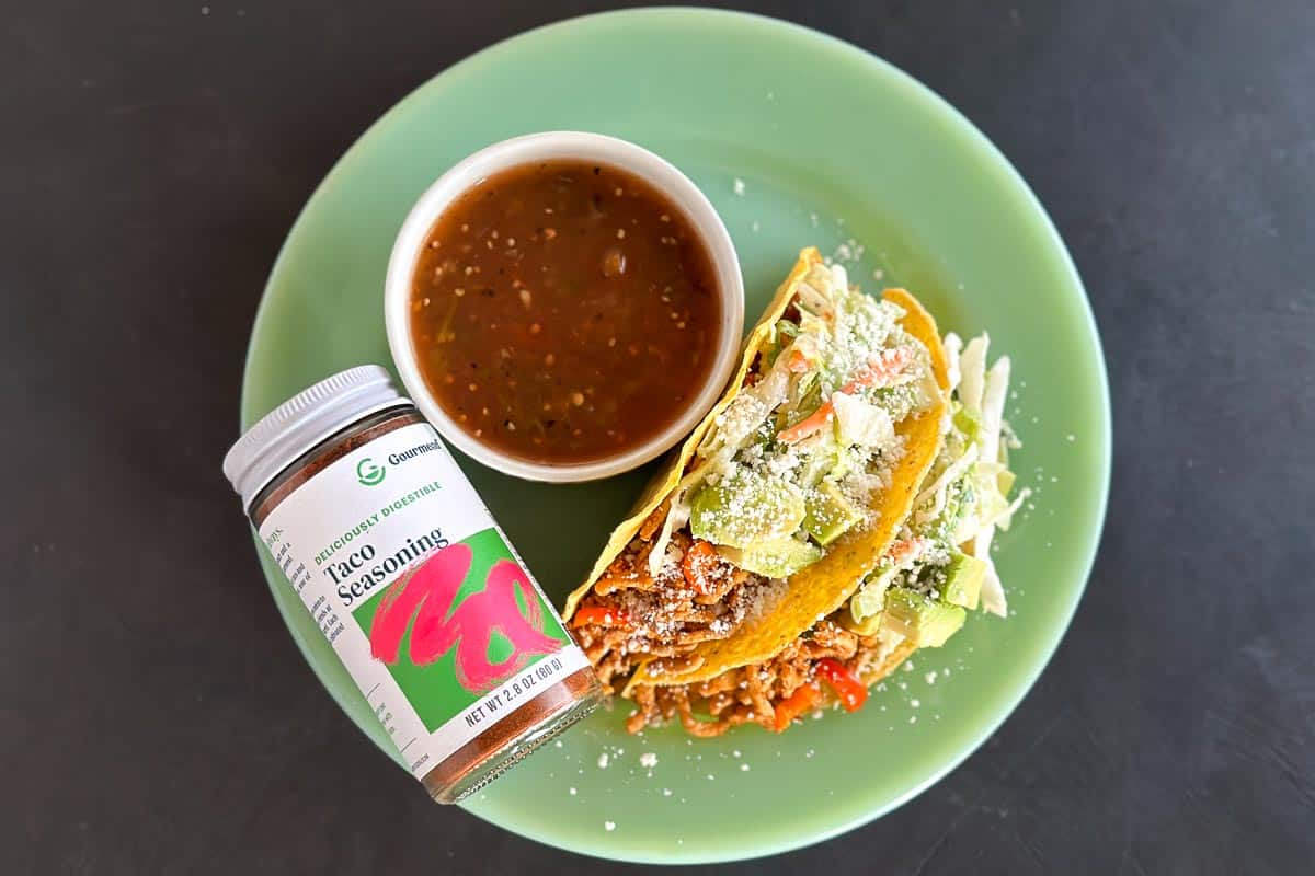 hard shell tacos on plate with Gourmend Taco Seasoning jar