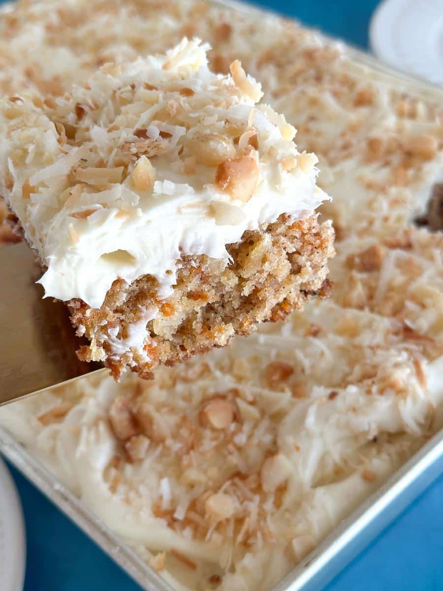 lifting piece of low FODMAP Tropical Carrot Cake out of pan on spatula.