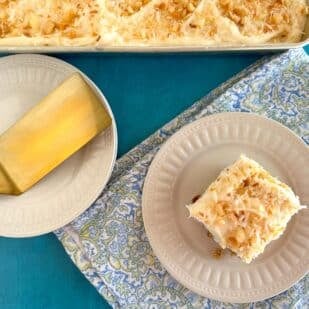 main image of Low FODMAP Tropical Carrot Cake with Coconut Cream Cheese Frosting, on pan, on plate, with gold spatula.