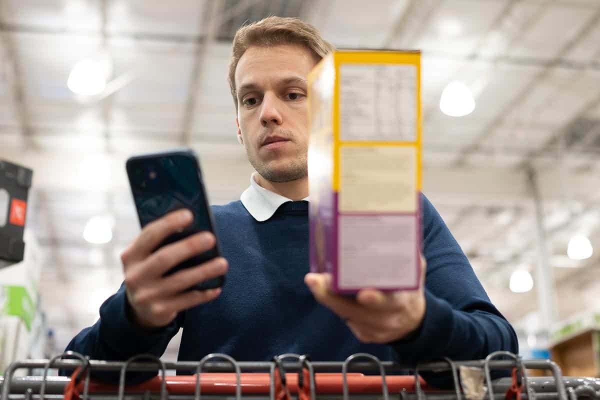man comparing label on box of food and on phone.