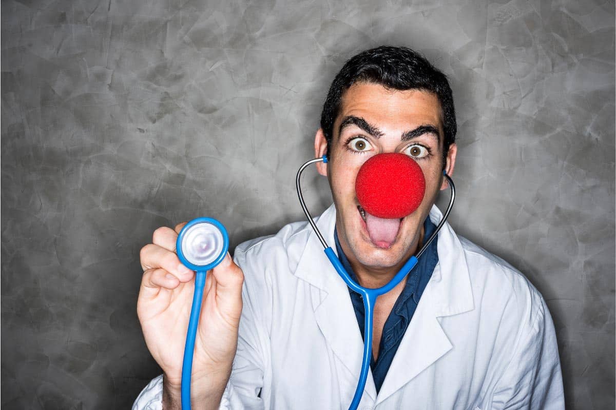 man with red clown nose in doctor coat