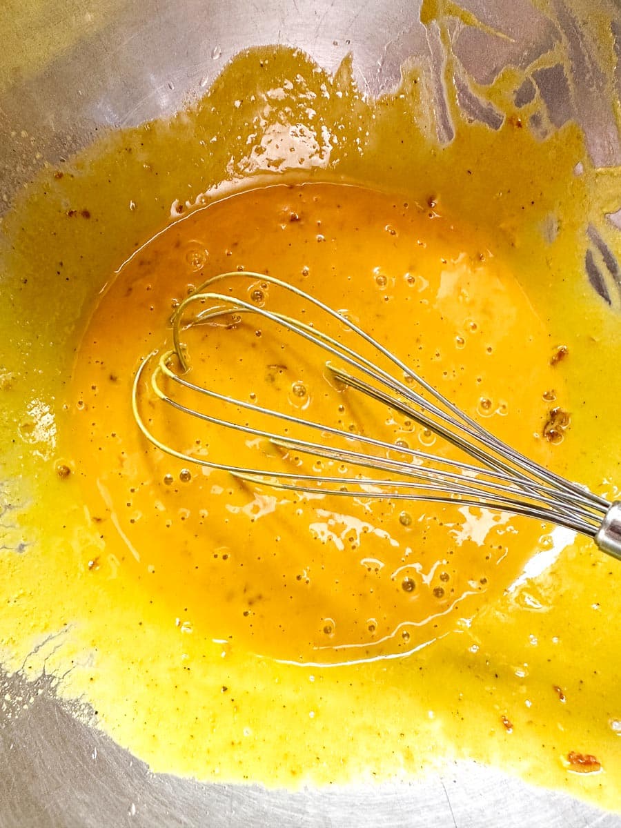 mustard BBQ sauce in bowl with whisk.
