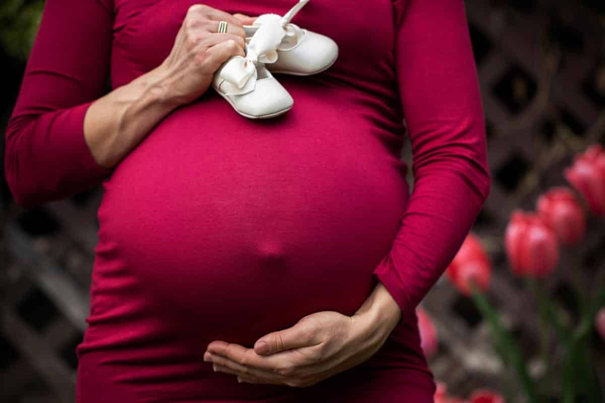 pregnant woman in red holding belly.