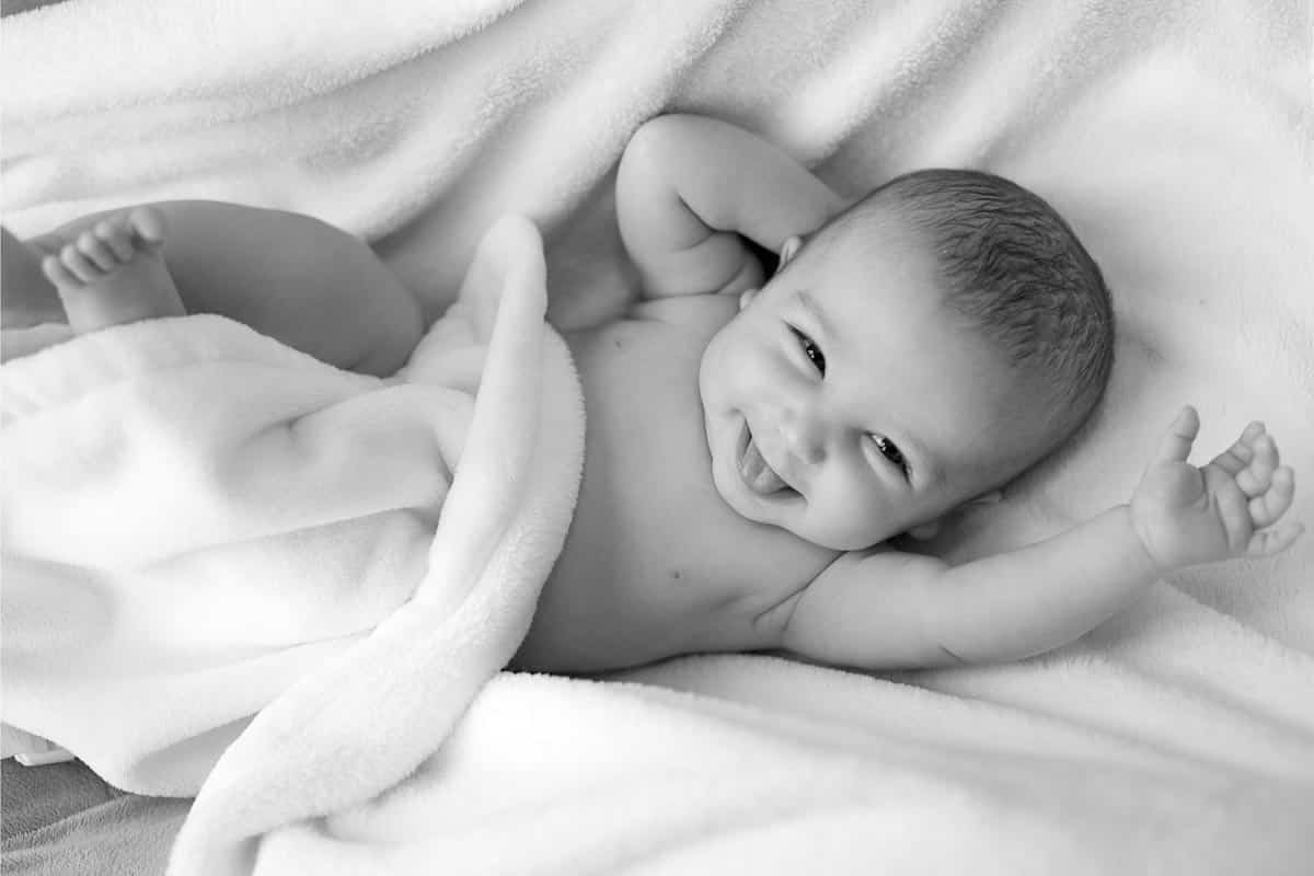 very happy newborn in white blanket.