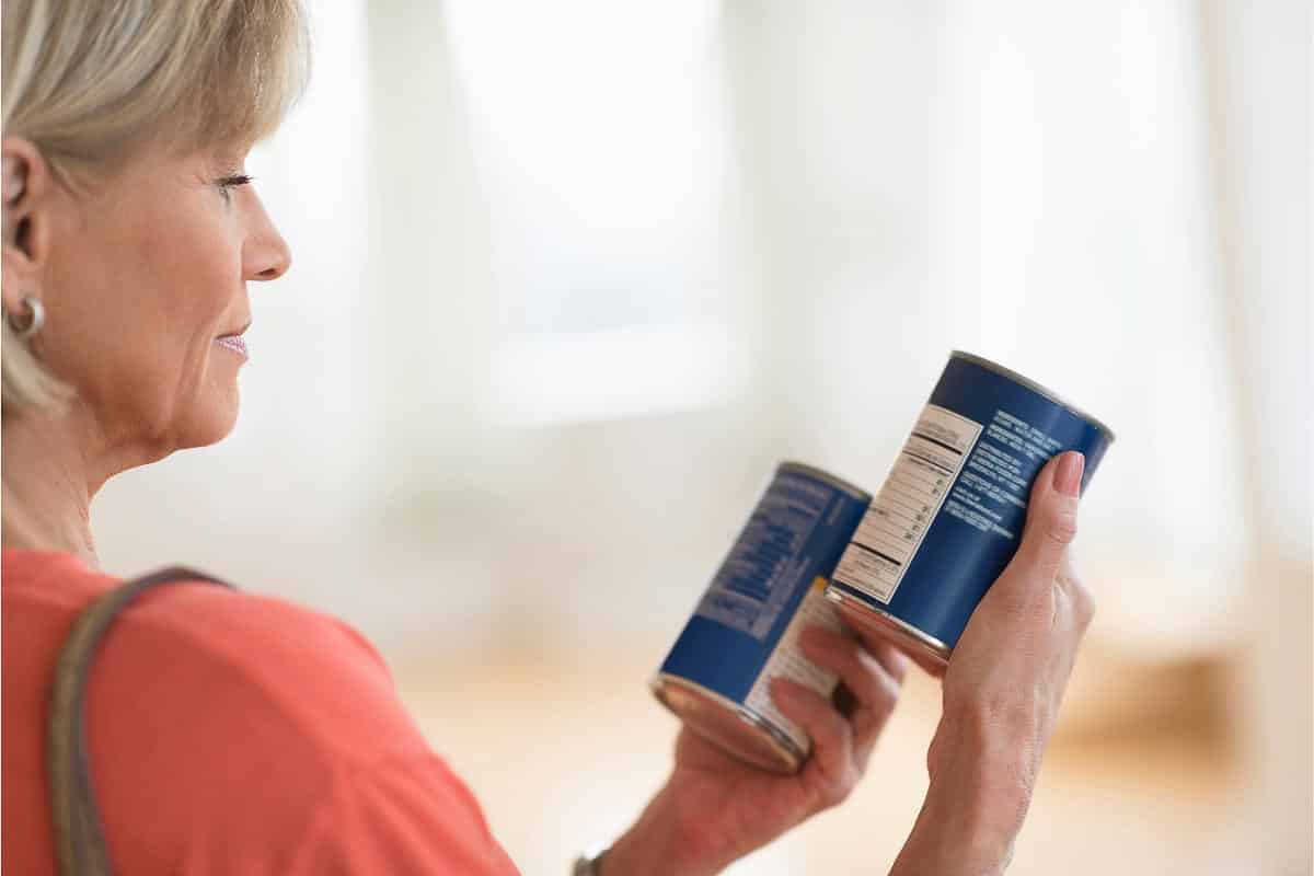 woman comparing labels on cans.
