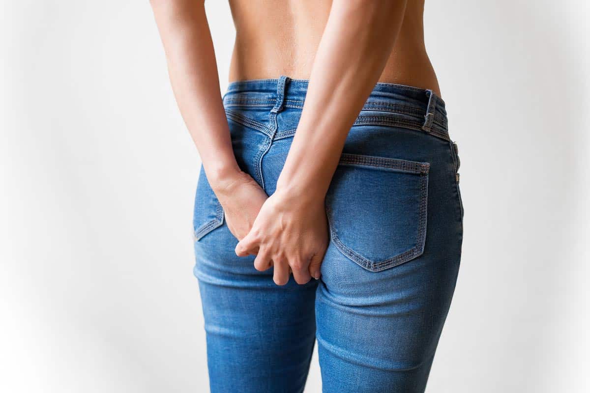 woman in jeans holding butt.