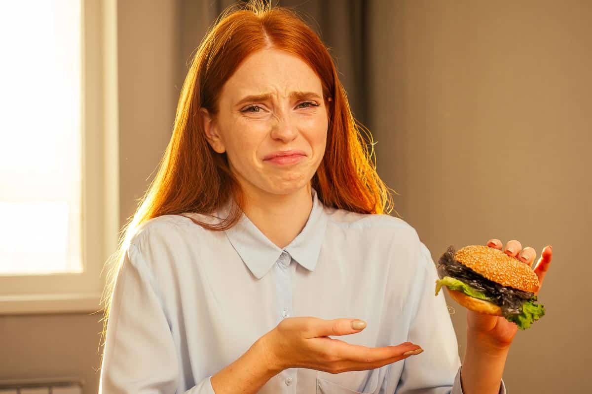 woman looking disgusted at burger.